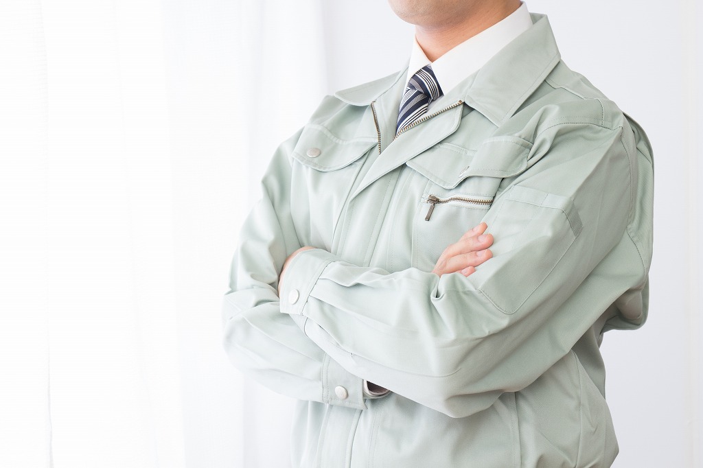 腕を組む作業服の男性